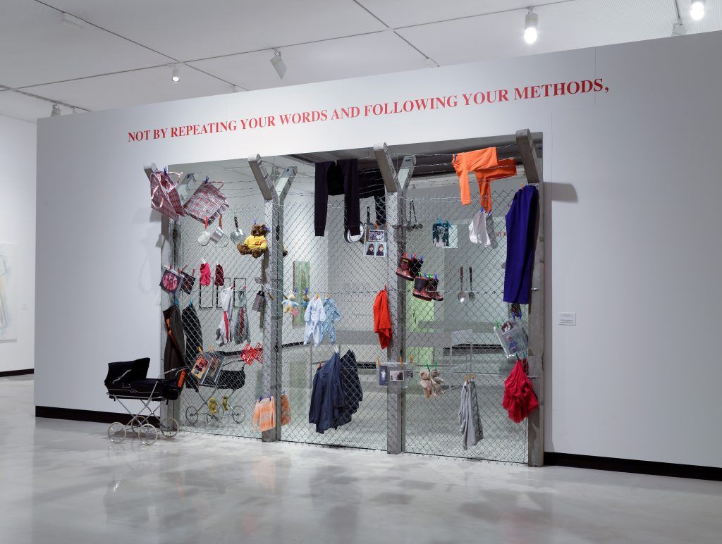 Cette installation fait référence au Camp de femmes pour la paix de Greenham Common au Royaume-Uni (1981-2000). Ce campement pacifiste protestait contre l'installation de missiles nucléaires sur la base Royal Air Force de Greenham Common, dans le Berkshire. Œuvre aux dimensions humanistes, Margaret Harrison y joue des contrastes marquant entre la vie et la guerre. Barbelés roses, nounours grillagés, fidèles témoins de l’absurdité des conflits. Margaret Harrison, Greenham Common (Common reflections), 1989-2013, béton, grillage, miroirs, vêtements, bottes d'enfant, landau, peluches, photographies et sacs plastiques, dim variables.